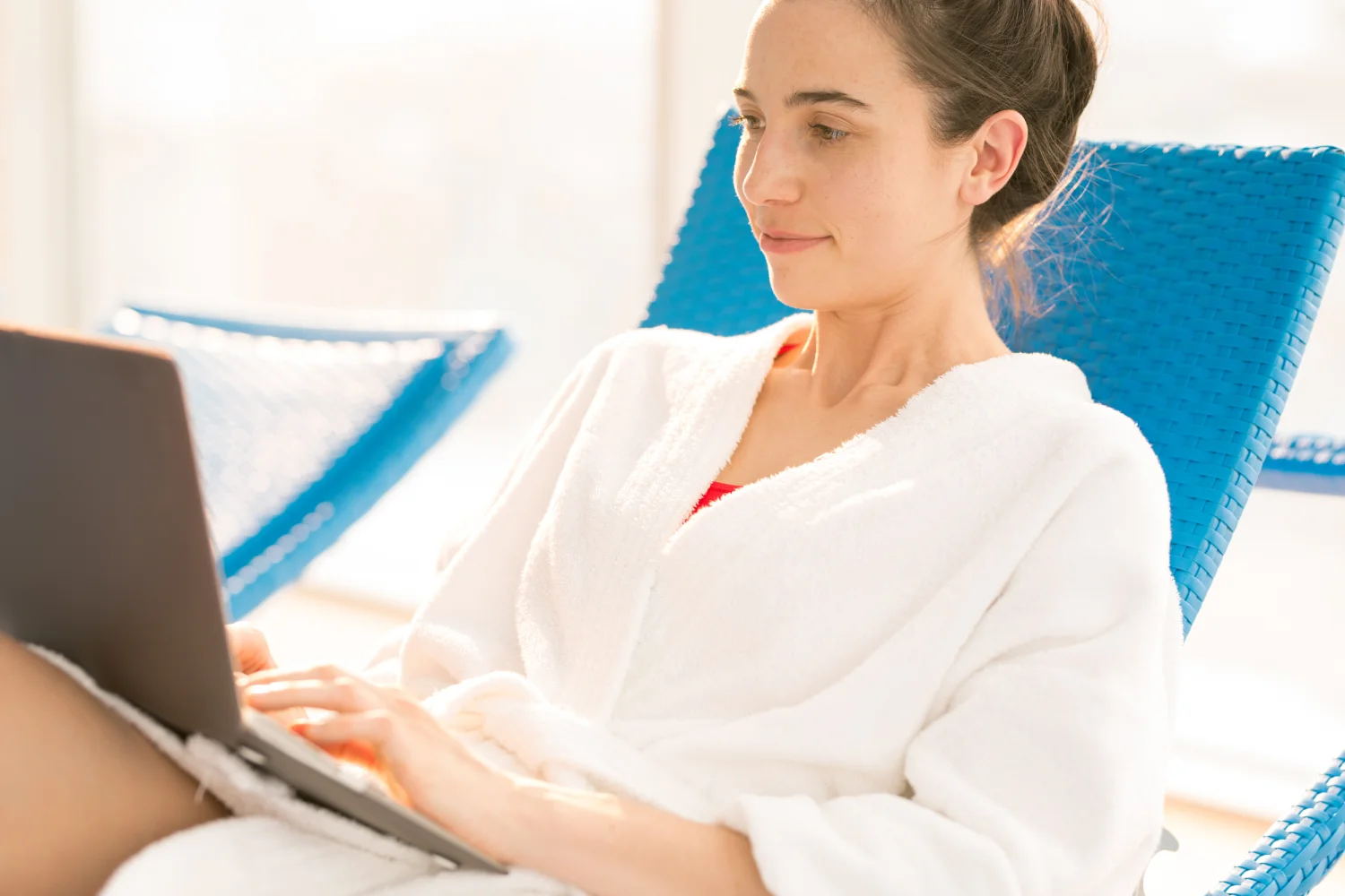 young-woman-bathrobe-resting-deckchair-summer-resort-browsing-net-front-laptop